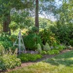 A lush green flower garden with statues.