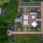 An aerial view of a home's backyard showcasing the landscaping of trees, bushes, plants, and flowers.